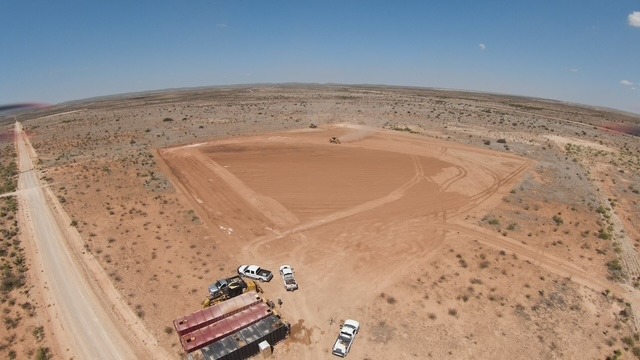 Aerial View of a Leveled Construction Pad in a Desert Landscape with Work Trucks