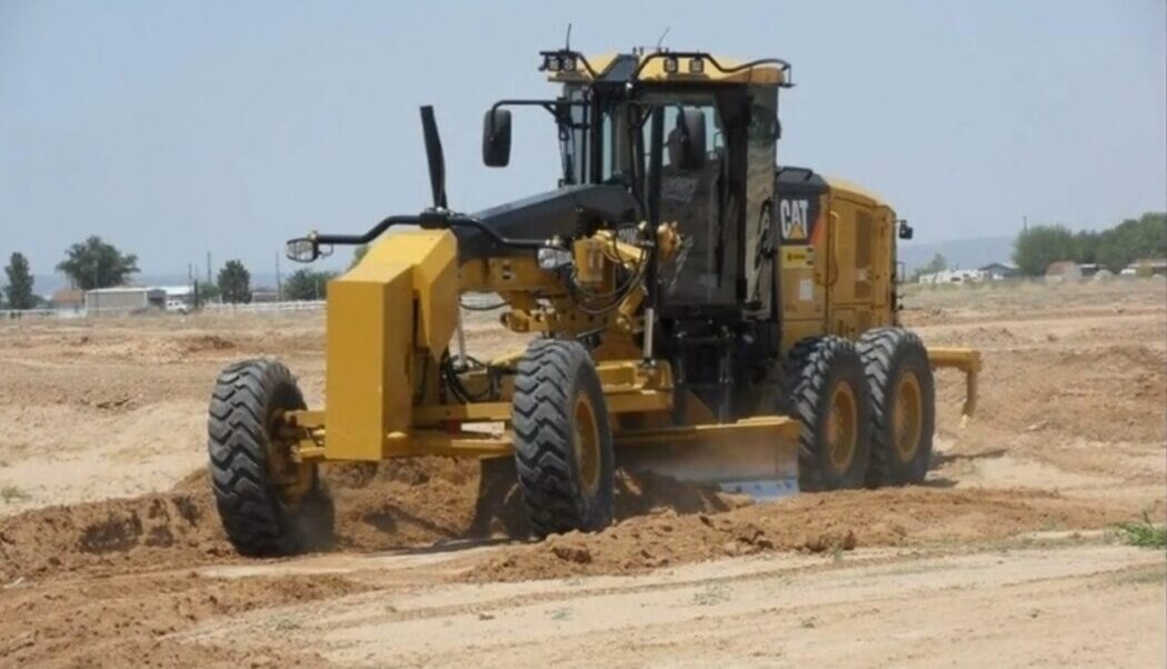 Motor Grader Leveling Dirt at a Construction Site During Daylight